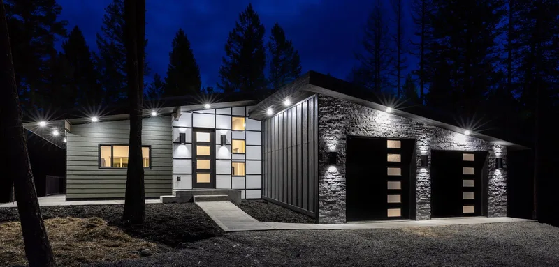 Modern Living Montana Built at dusk: the lit mountain modern home under a blue evening sky