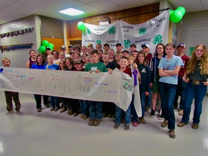 Flathead County 4-H members gathered with a banner and green balloons