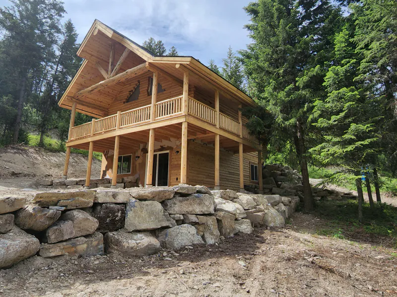 A handcrafted log home on a mountainside meadow, by Built Right in Montana