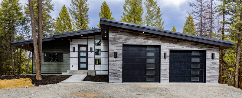A finished modern Montana home among the pines, stone and board-and-batten with a deep overhang