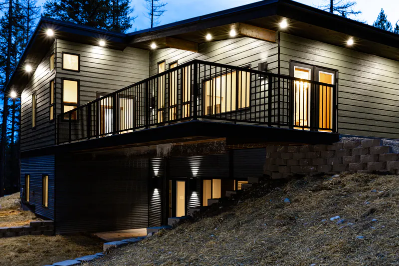 A modern Montana home lit at night under the northern lights