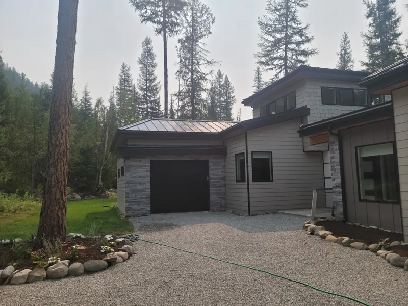 A finished Built Right home at the end of its drive, framed by Montana pines